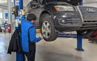 Mechanic inspecting SUV on hydraulic lift