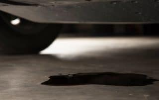 Oil leak forming puddle under car