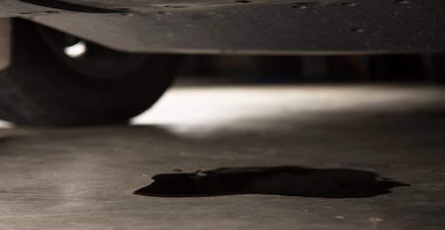 Oil leak forming puddle under car