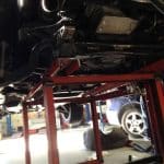 Car underside on red lift in garage