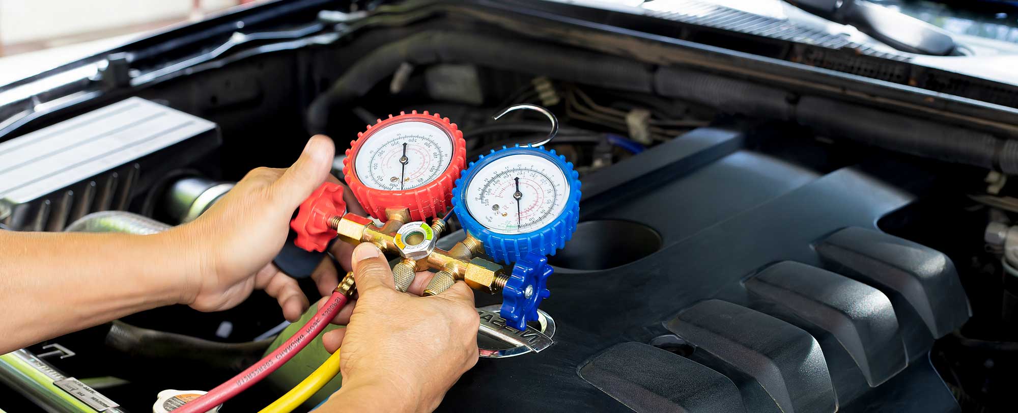 Technician checking car AC pressure with gauges