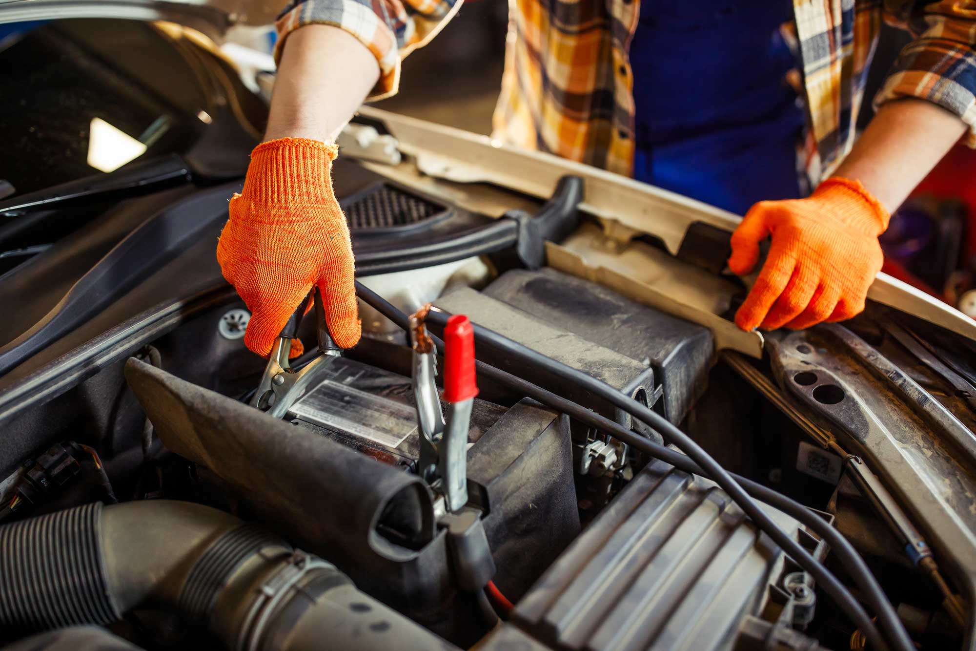 Person connecting jumper cables to car battery