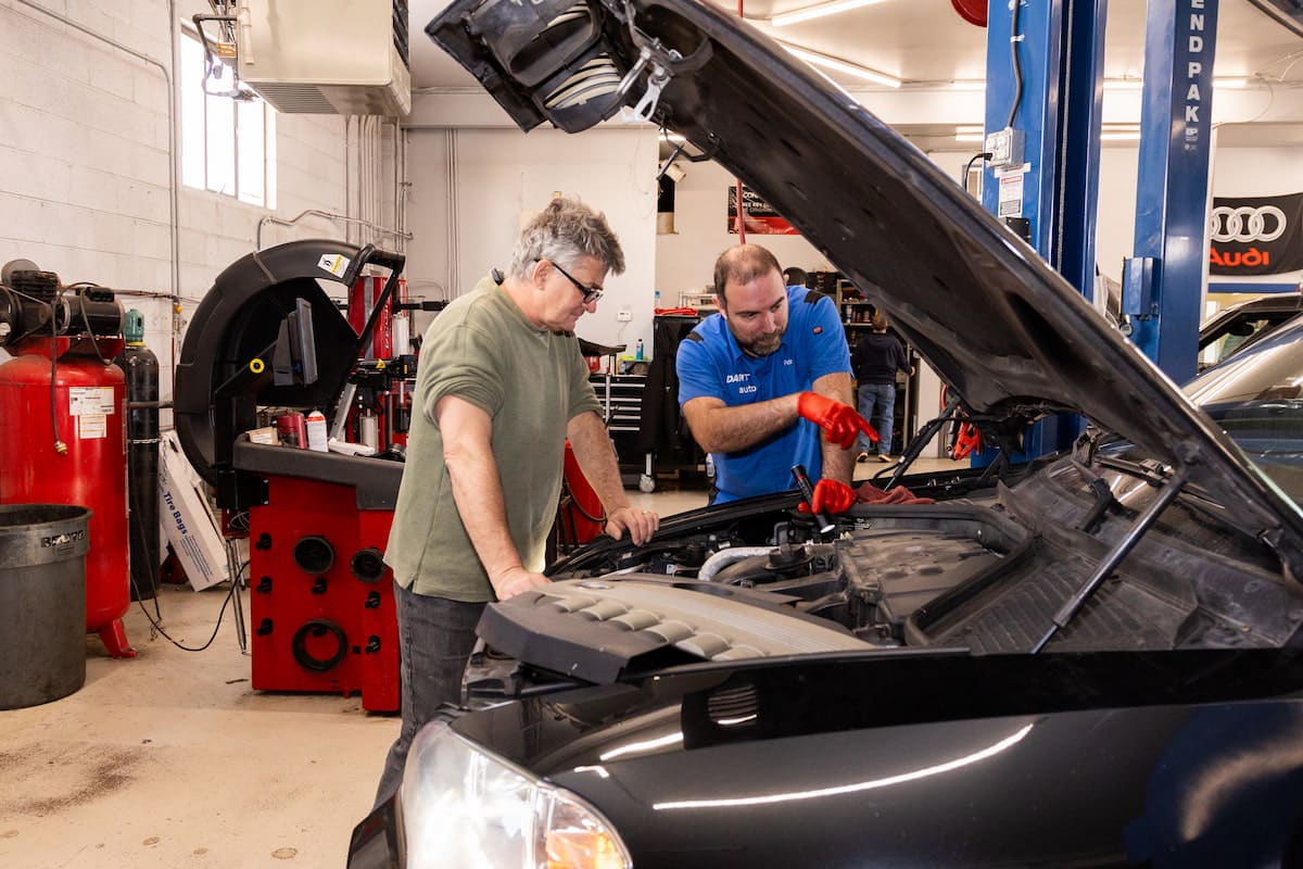 European Auto Scheduled Service Maintenance in Denver image Mechanic explaining car engine to customer in shop