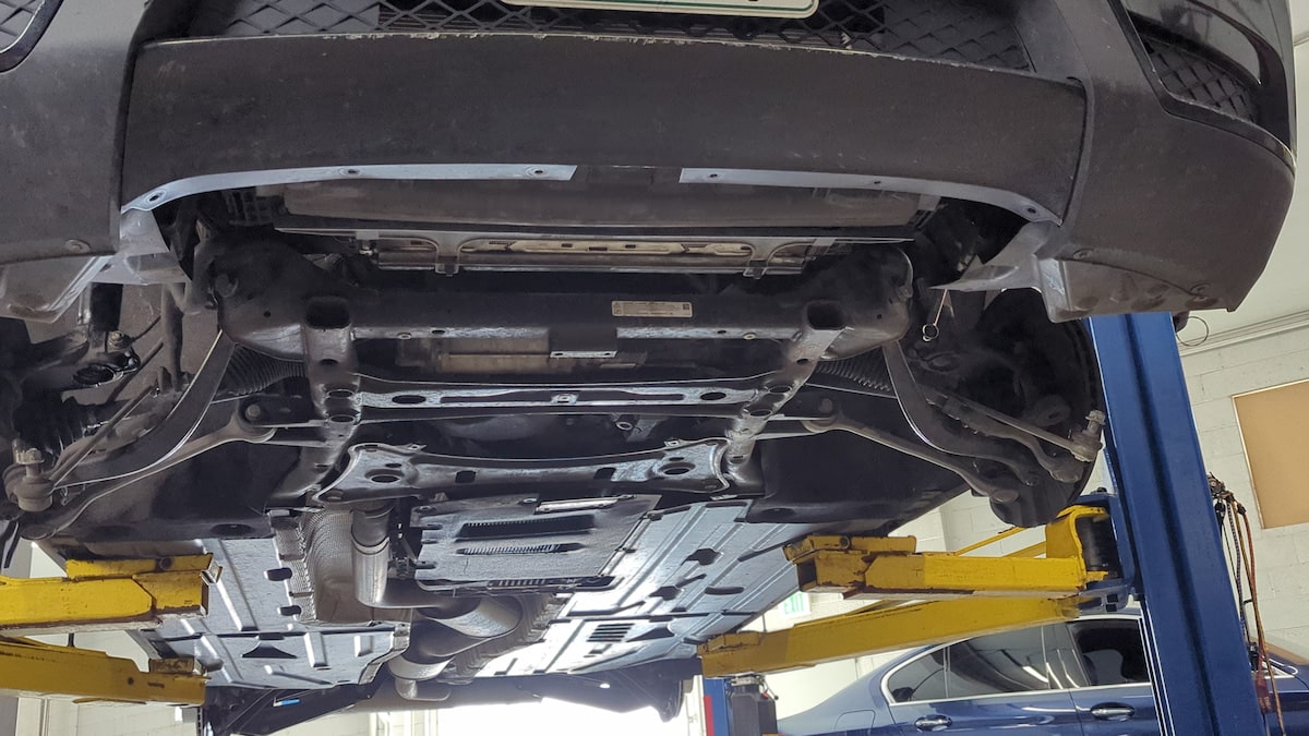 European Auto Steering Repair in Denver image Underside of car on hydraulic lift in garage
