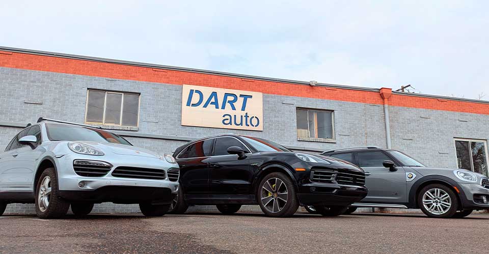 Three luxury cars parked outside auto dealership