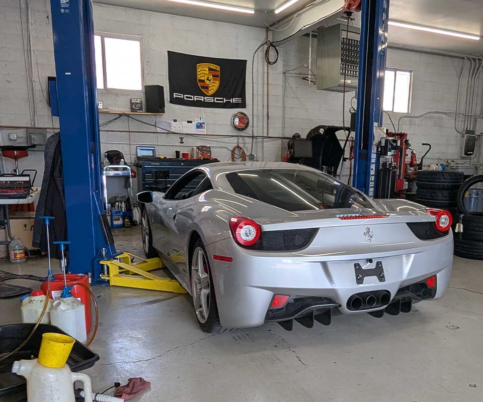 Silver Ferrari on lift in auto shop