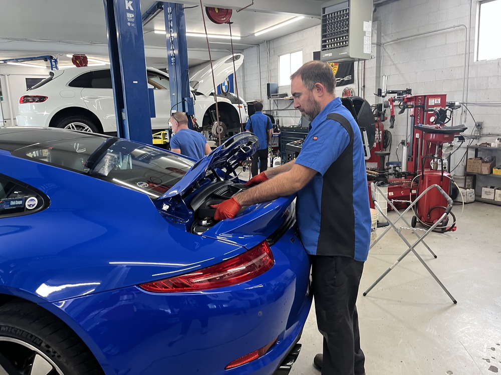Mechanic servicing blue sports car in auto shop