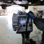 Mechanic lifting car transmission in auto repair shop