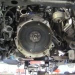 Car engine underside with exposed flywheel assembly