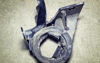Broken metal automotive bracket on concrete floor