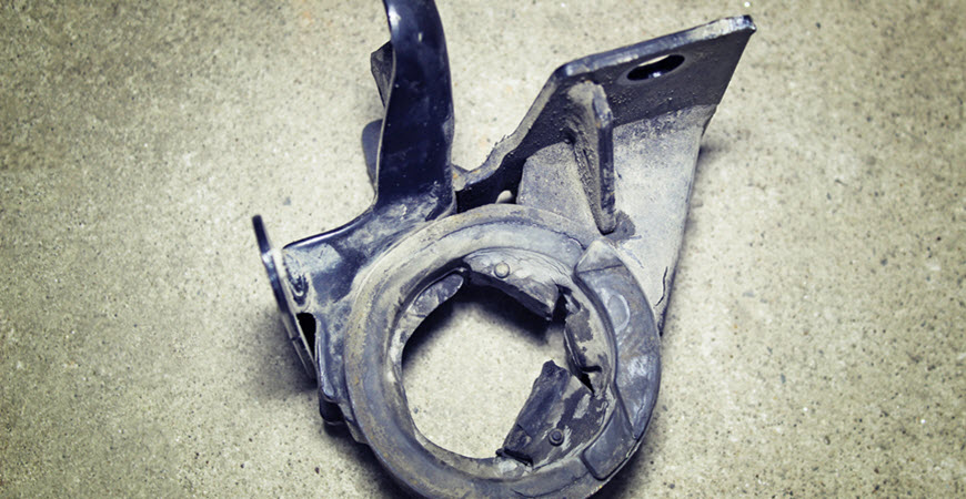 Broken metal automotive bracket on concrete floor