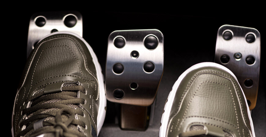 Sneakers pressing car pedals in vehicle footwell