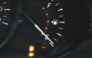 Car dashboard fuel gauge near empty with warning light