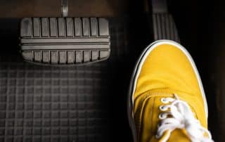 Yellow sneaker pressing car accelerator pedal