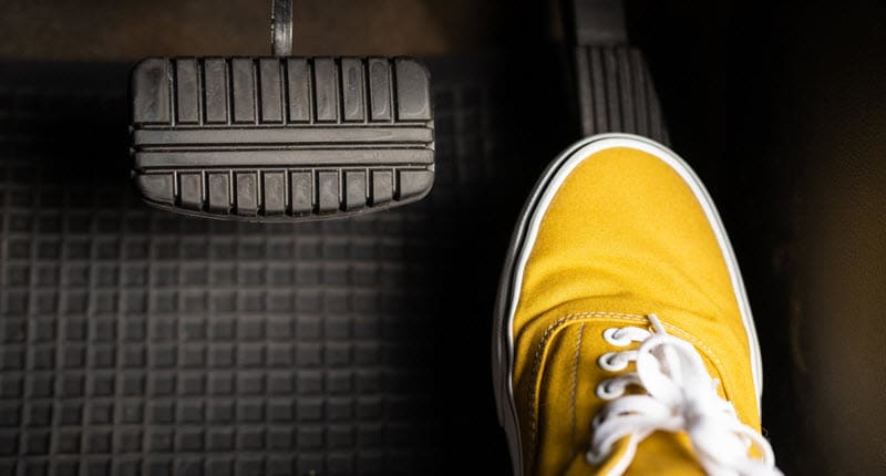 Yellow sneaker pressing car accelerator pedal