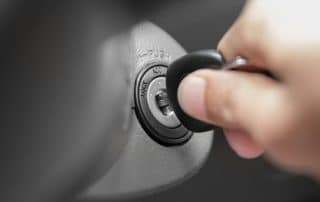 Hand inserting car key into ignition switch