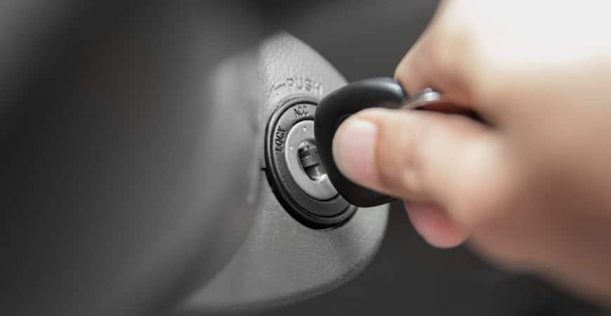 Hand inserting car key into ignition switch