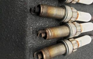 Four used spark plugs on dark surface