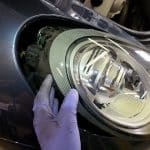 Gloved hand removing car headlight assembly