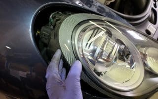 Gloved hand removing car headlight assembly