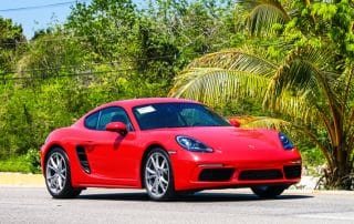 Red Porsche sports car on tropical roadside