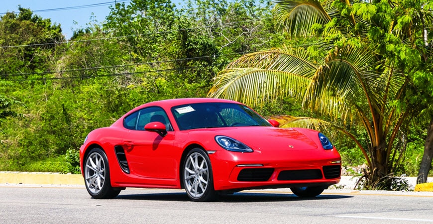Red Porsche sports car on tropical roadside