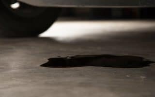 Dark oil puddle under parked vehicle