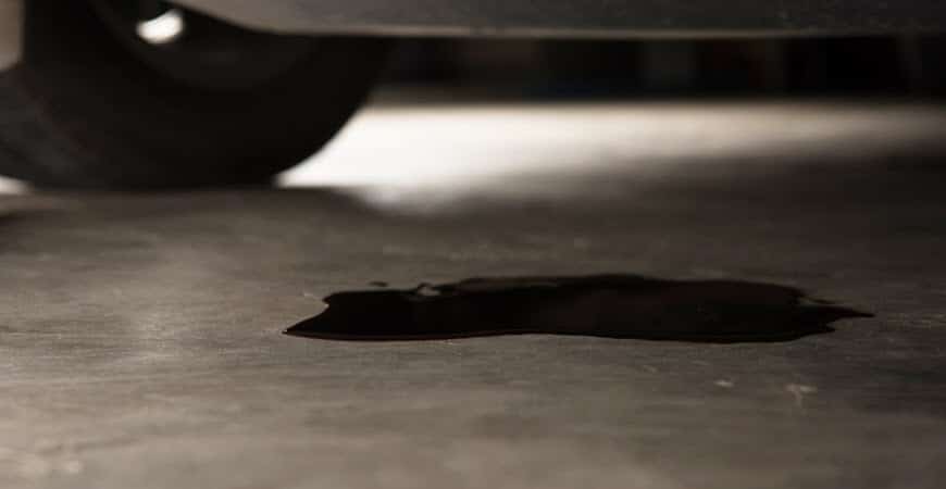 Dark oil puddle under parked vehicle