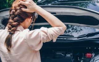 Woman examining car engine with open hood