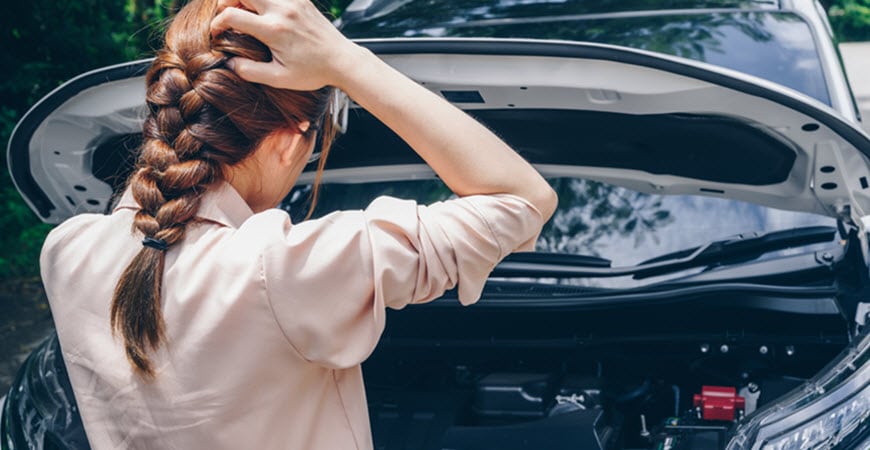 Woman examining car engine with open hood