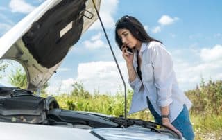Woman on phone beside broken-down car