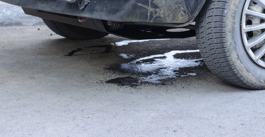 Car leaking fluid onto pavement near front tire