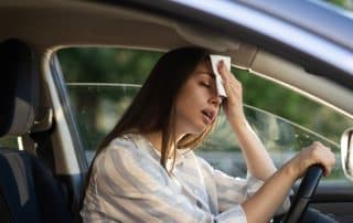 Woman in car holding tissue to forehead