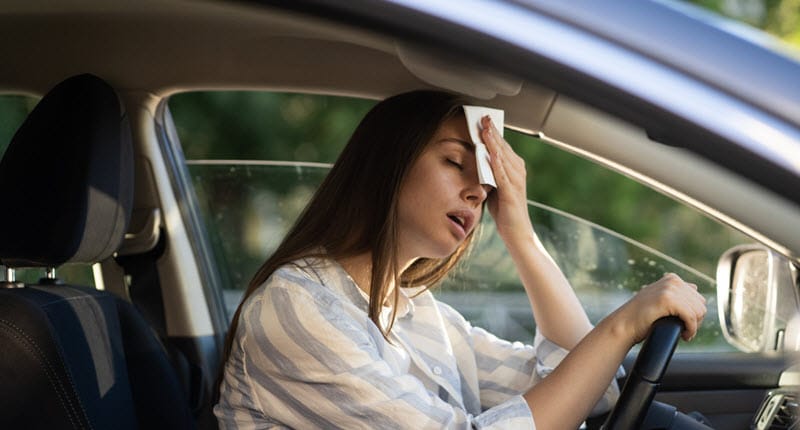 Woman in car holding tissue to forehead