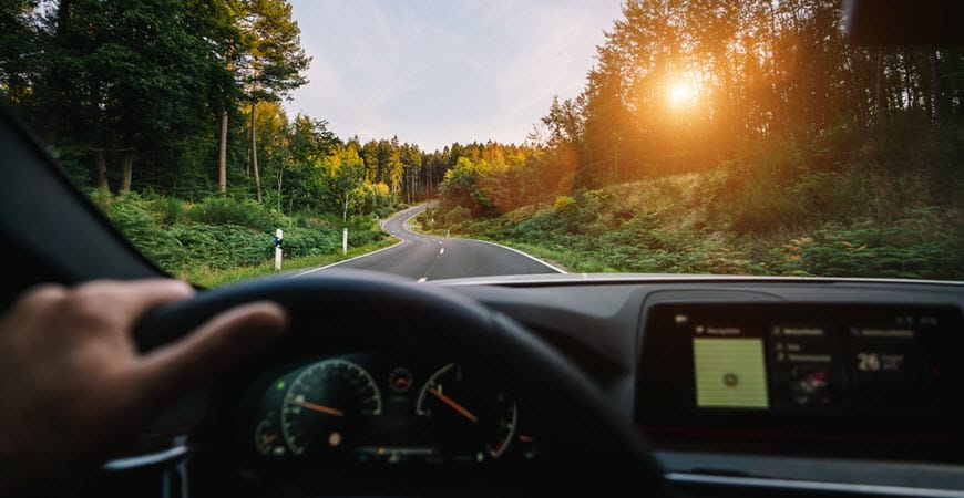 View from car driving on forest road at sunset