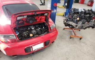 Red sports car with engine removed in workshop