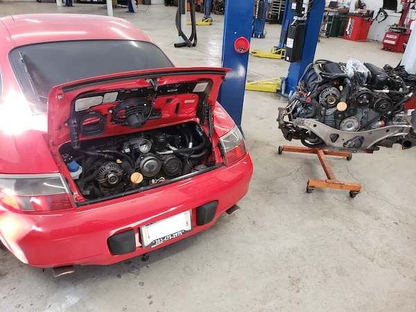 Red sports car with engine removed in workshop