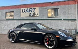 Black Porsche convertible parked outside auto dealership