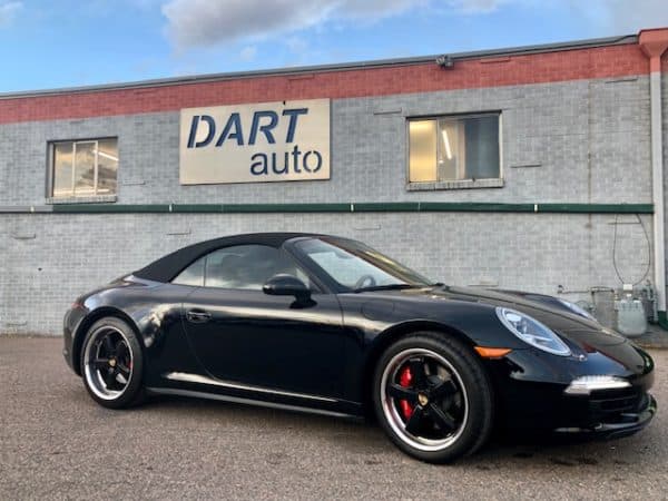 Black Porsche convertible parked outside auto dealership