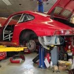 Red classic sports car on lift in garage