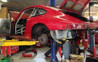 Red classic sports car on lift in garage