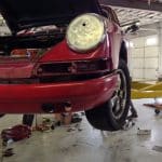 Red classic Porsche on lift in garage