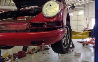 Red classic Porsche on lift in garage