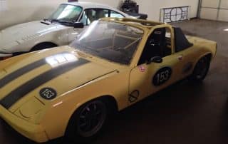 Yellow vintage Porsche race car in garage