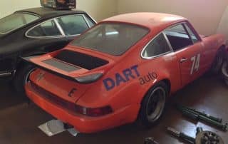 Orange vintage Porsche race car in garage