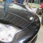 Black car with hood slightly open in garage