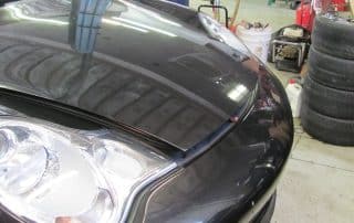 Black car with hood slightly open in garage