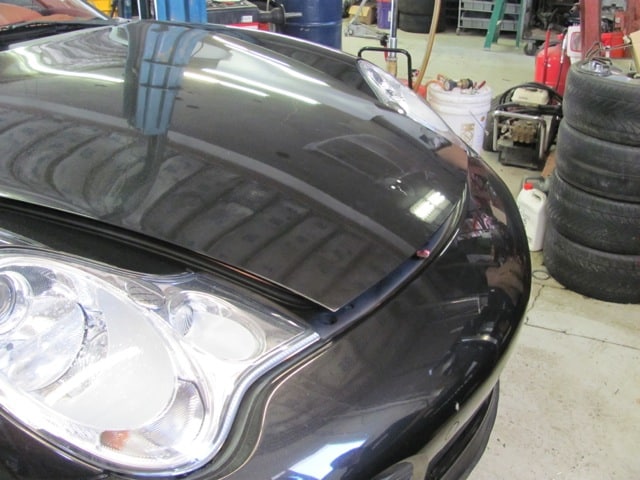 Black car with hood slightly open in garage