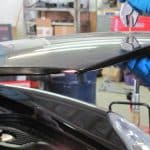Mechanic adjusting car hood in auto workshop
