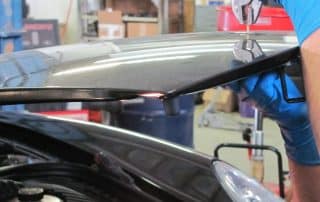 Mechanic adjusting car hood latch in workshop